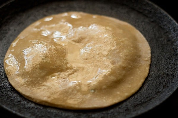 the aloo paratha has been brushed with oil and is beginning to puff up.