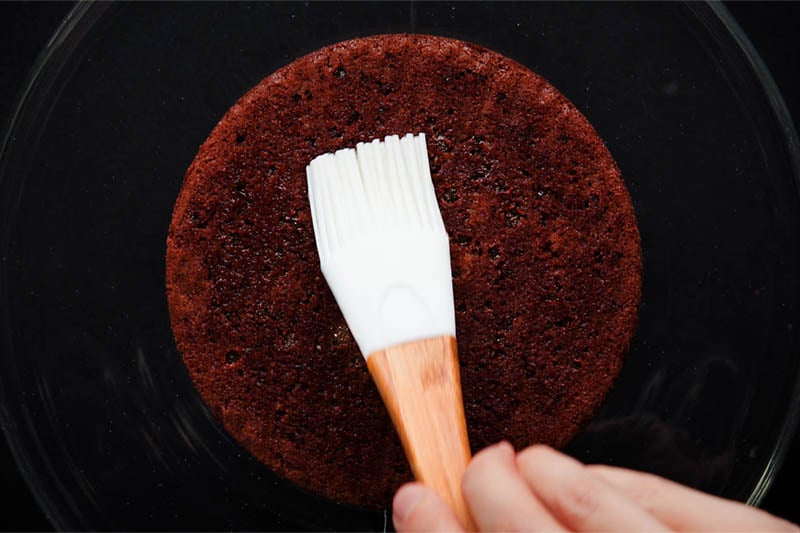 brushing bottom layer of chocolate sponge with sugar syrup