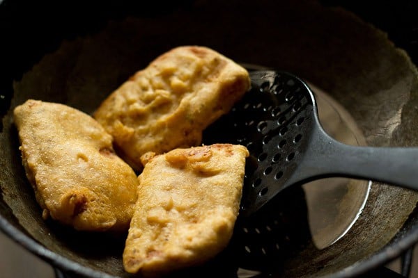 removing golden, crisp, bread bajji with a slotted spoon