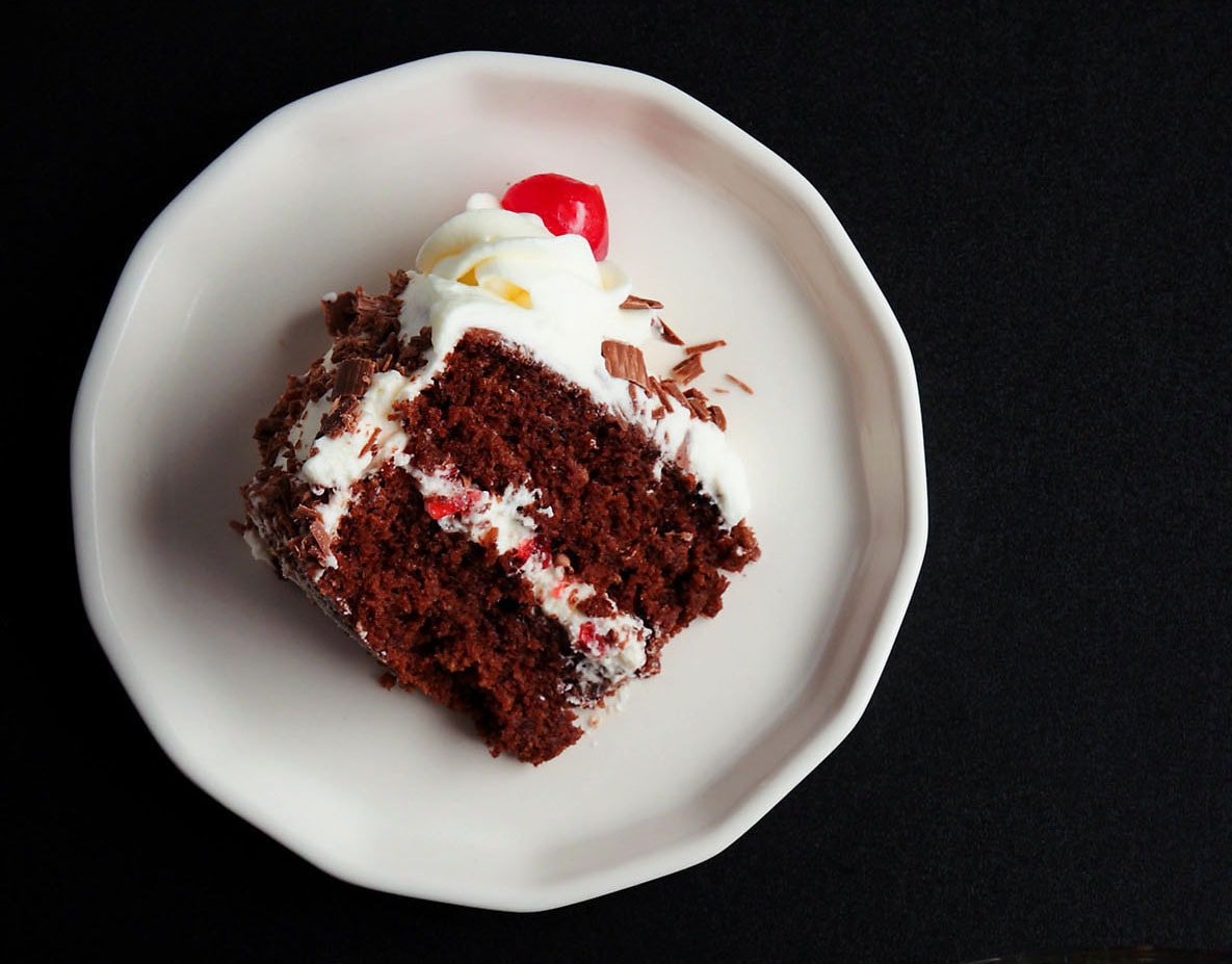 overhead shot of one slice of black forest cake on its side on a white plate