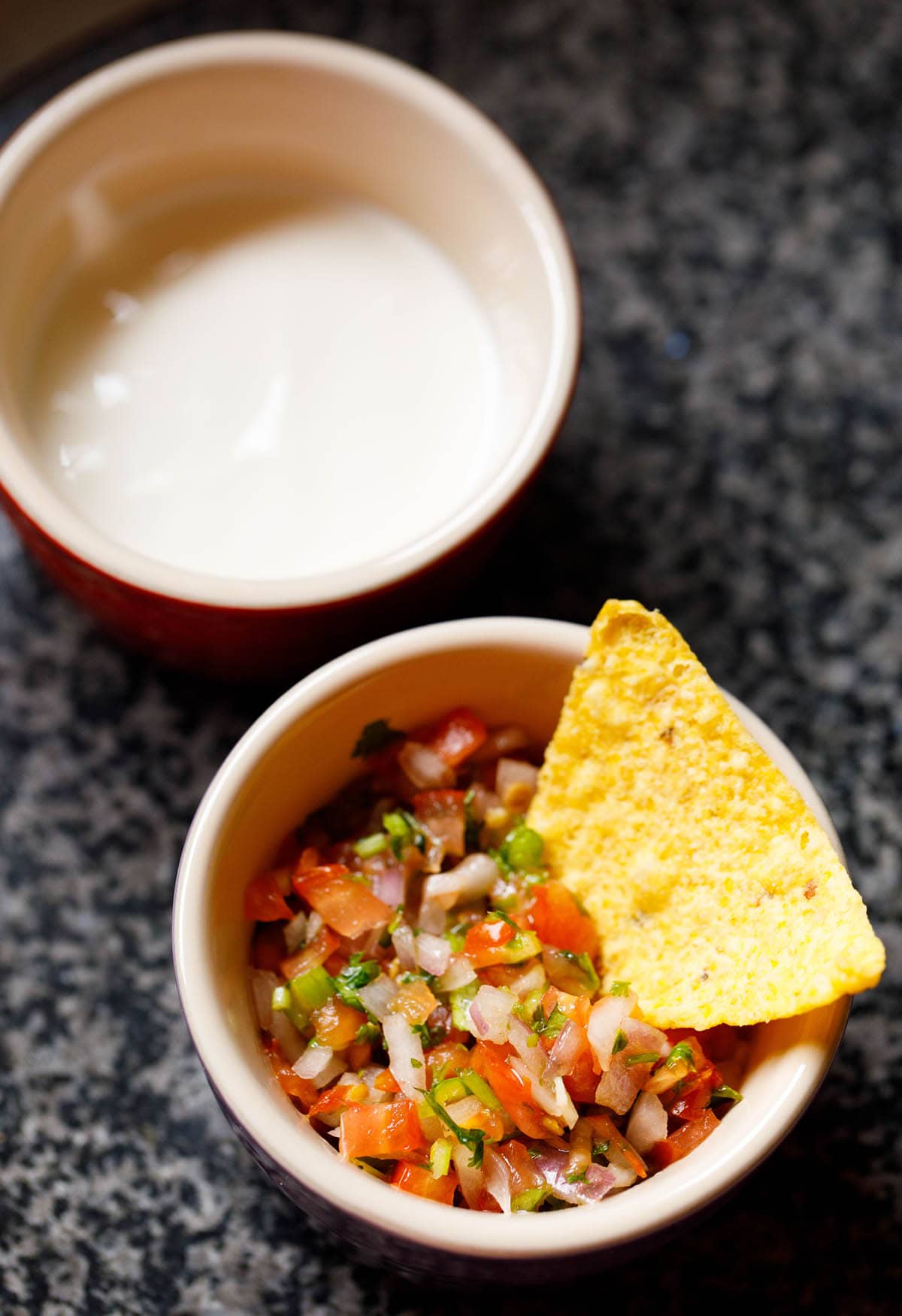 salsa fresca in a bowl with a nacho chip in it.